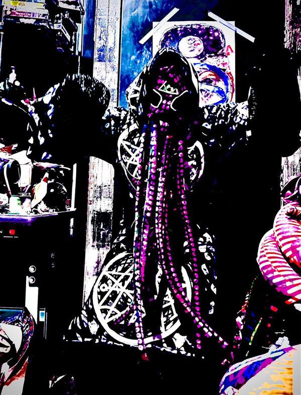 Mike Knives stands in an ominous pose, wearing his Eldrich tentacle mask and wizard cloak